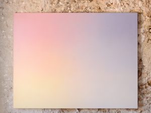 Une peinture abstraite accrochée sur un mur en pierre.